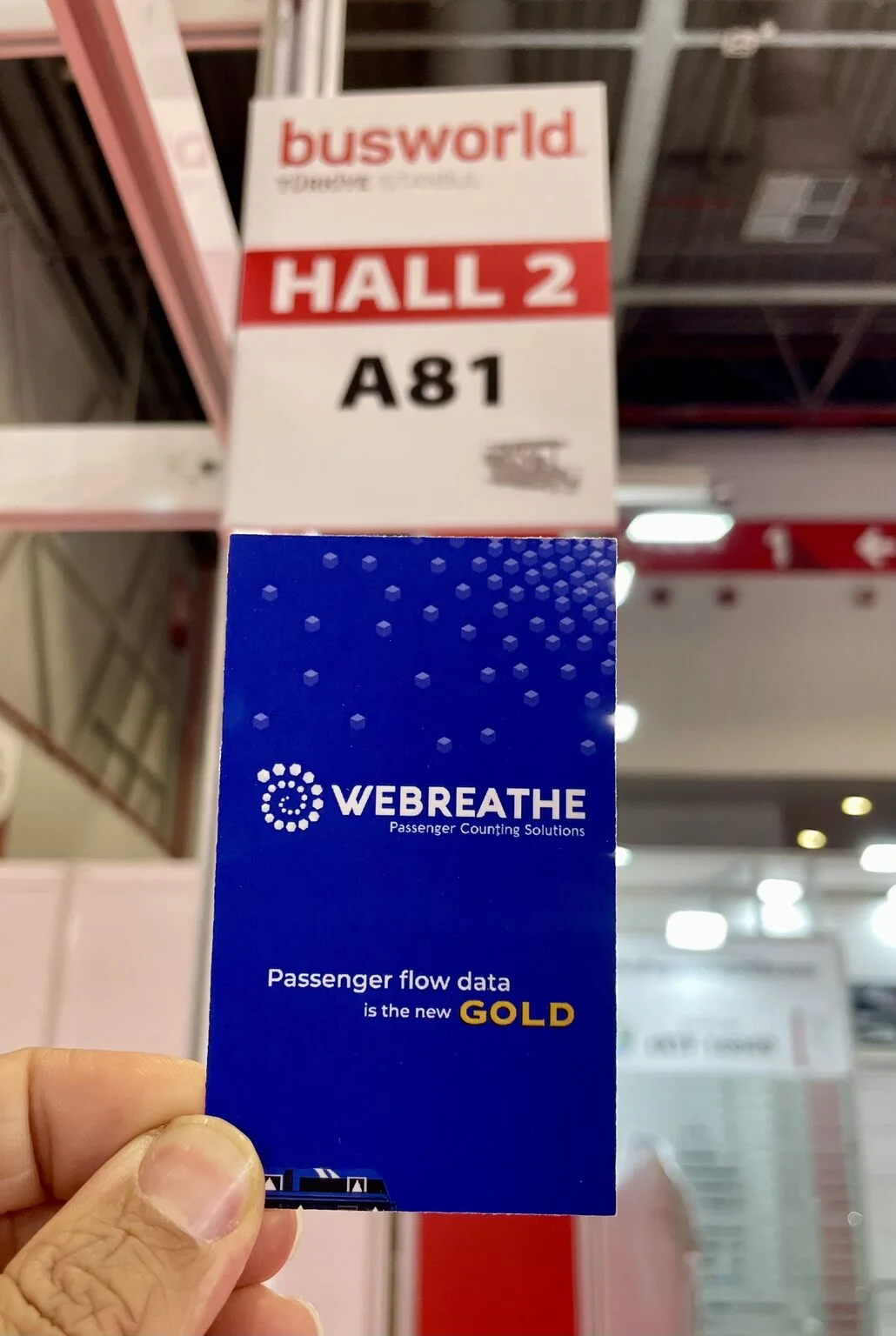 Hand holding a WEBREATHE card beneath the Busworld Hall 2 and Booth A81 sign
